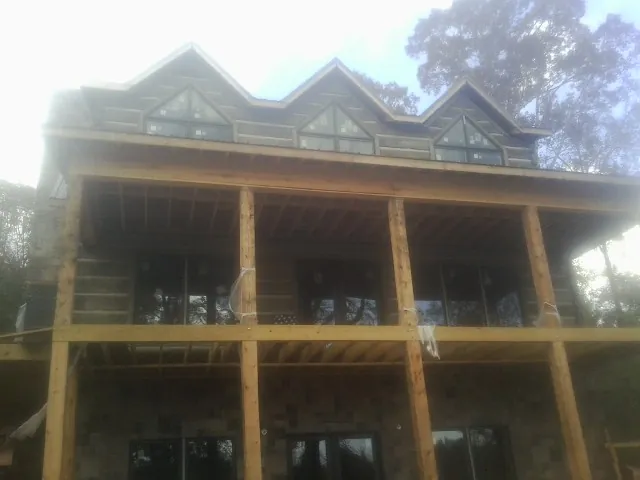Dormers and porch framing on a large log home under construction — Roof Coating work by our crew in Glen
