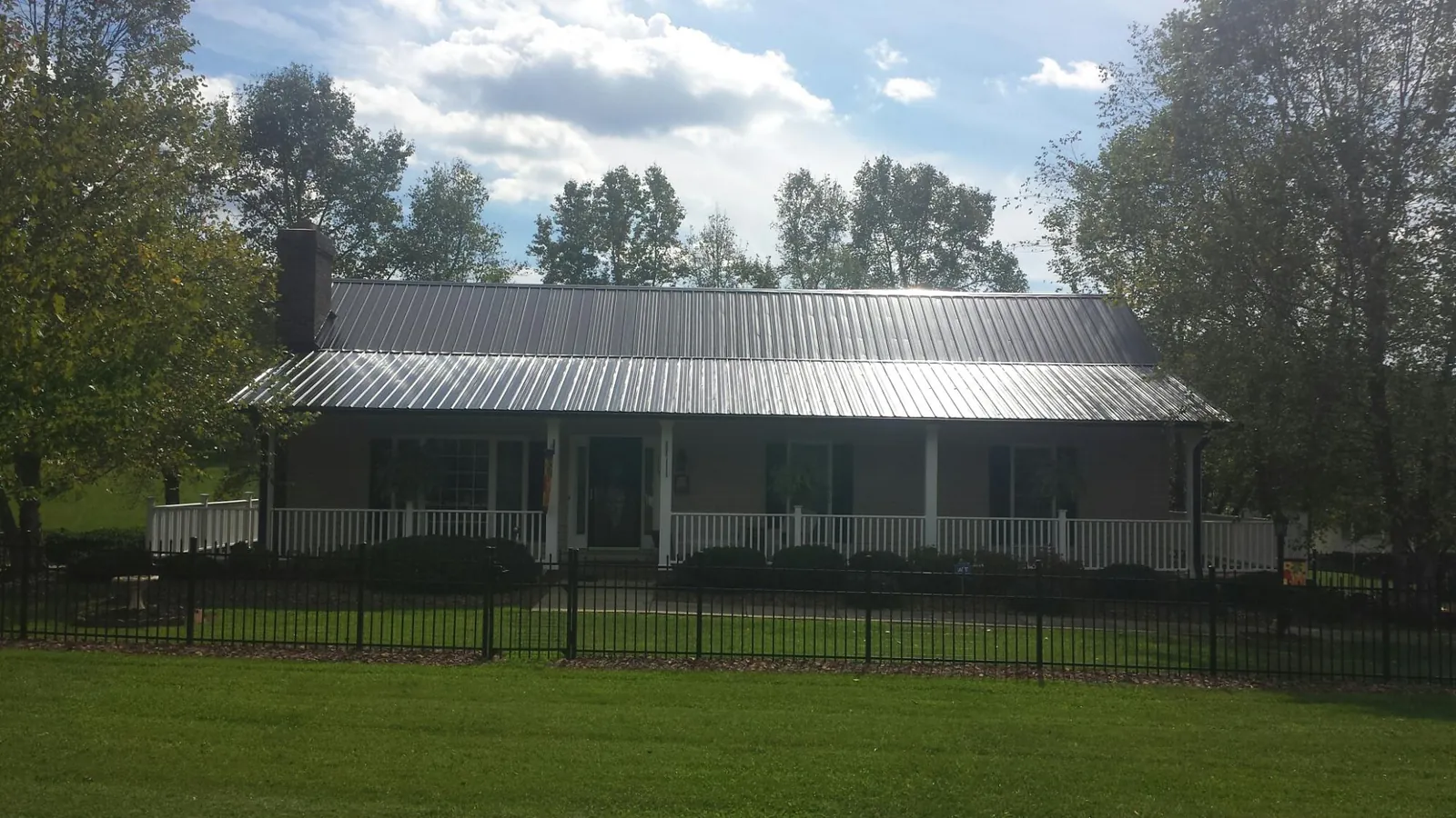 Gray metal roof on a brick ranch with a full width front porch — Gutter Guard Installation work by our crew in Glen